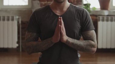 Lotus yoga erkek kapalı poz. Ahşap zeminli ve büyük pencereleri olan stüdyoda yoga yapan genç bir adam. Özgürlük, sağlık ve yoga konsepti. Kamera uzaklaştırma