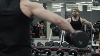 Adam asansör-up yapıyor, elinde halter tutan, omuz kasları için egzersiz