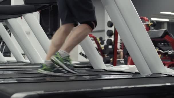 Manliga ben som körs på löpbandet i gymmet. Närbild av fötter som körs på löpband — Stockvideo