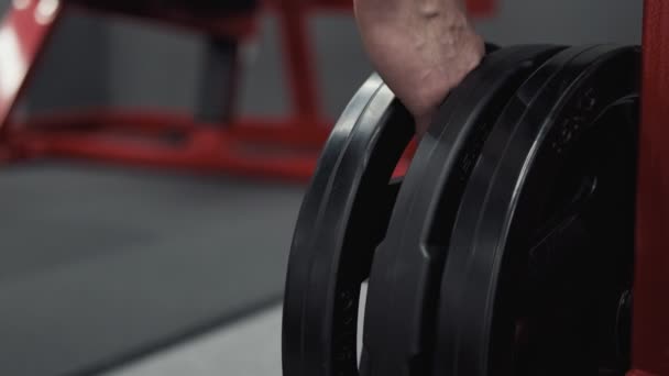 Trainer putting and removing weight plates from barbell, preparing gym equipment — Stock Video