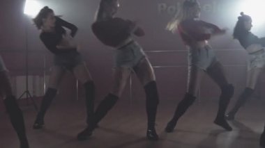 Dans salonunun keyfini çıkaran kadınlar karanlık stüdyoda duman ve ışıkla hareket ederler.