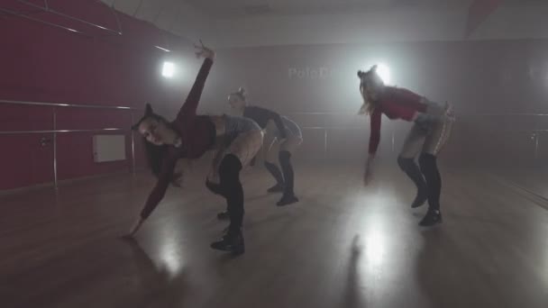 Ženy těší tanec pohybuje v tmavém studiu s kouřem a osvětlením — Stock video