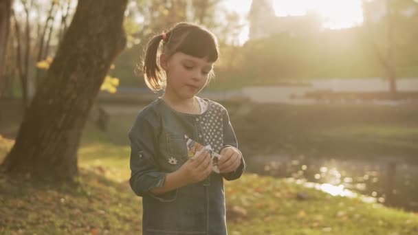 Portrait de petite fille regardant la caméra avec bateau en papier dans le parc d'automne. Jolie fille dehors. Portrait avec rayons de soleil 