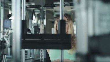 Fitness sarışın kız omuzlar için egzersiz yapıyor. Spor salonunda ağırlık kaldıran genç kadın. Yavaş çekimde fitness merkezinde sarışın kadın Orta çekim.