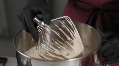 Çırpıcıdan damlayan hamur. Baker kek yapmak için metal kase malzemeyi karıştırır. Kadın para hazırlar. Eldivenli eller