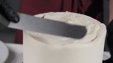Adım adım. Siyah eldivenli kadın eli sünger kek üzerine krem şanti beyaz krema serpişiyor. Baker spatula kullanarak krema ile pasta hazırlanıyor. Krem şanti ile Baker yumuşatma kek