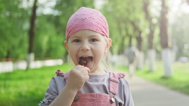 Niña Disfrutando Piruleta Mirando Cámara Niño Vestido Rosa Comiendo Dulces — Vídeo de stock