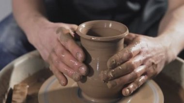 İnsan, çömlekçi tekerleğinde ya da çömlekçi torna çömlekçiliği üzerinde sürahi oluşturur. Ellerin yakın yavaşça kilden sürahi oluşturun. El yapımı. Zanaat.