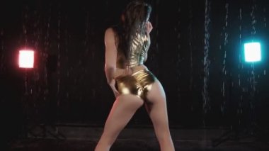 Seksi kız dans twerk. Kısa şortlu tabaklanmış kadın vücudunu hareket ettirir. Yağmur, mavi ve kırmızı ışıkla iç mekanlarda twerking kadın. Orta atış