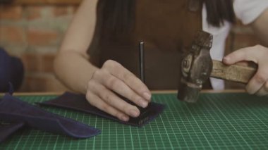 Deri ustası deride delikler açar. Yavaş çekimde delik açmak için çekiçle deriye basın. Esnaf delik yumruklar.