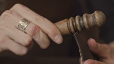 Yavaş hareket aşındırıcı ahşap sopa ile el yapımı deri cüzdan parlatma profesyonel kadın esnaf elleri yakın çekim. El yapımı deri cüzdan üretim süreci.
