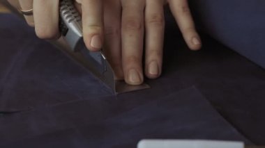 Deri işçisi bronzlaşma dükkanında deri ürünleri ile çalışır. El yapımı deri eşyalar. Mavi derinin elle kesilmesi