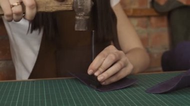 Delik açmak için çekiçle deriye basın. Profesyonel kadın deri deri delikler yapar. El yapımı deri eşyalar