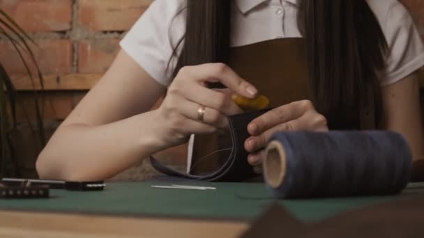 工匠传播蜡 专业女性工匠手抛光皮革钱包边缘与一块蜡 大师在车间里做钱包 — 图库视频影像