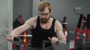 Gözlüklü sakallı adam spor salonunda egzersiz bisikleti üzerinde çalışıyor. Yavaş çekimde spor salonunda bisikletüzerinde redhead adam eğitim. Spor ve fitness konsepti