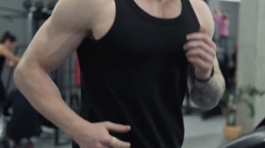 Genç kızıl saçlı atletik adam egzersiz ve spor salonunda koşu bandı üzerinde çalışan yakın. Uhd yavaş hareket spor salonunda koşu bandı makineüzerinde çalışan sakallı adam