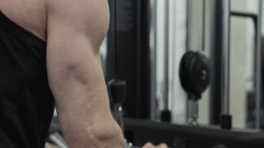 Güçlü kaslı adam tricep performans egzersiz sırasında downs çekin. Spor salonunda kablo makinesi çekerek odaklanmış adam eğitim triceps kasları