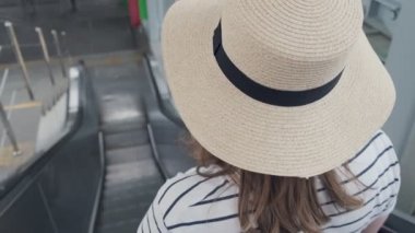 Şapkalı genç bir kadın hareket halindeki merdiven boşluğundan çıkıyor. Kopyalama alanı ile yakın çekim