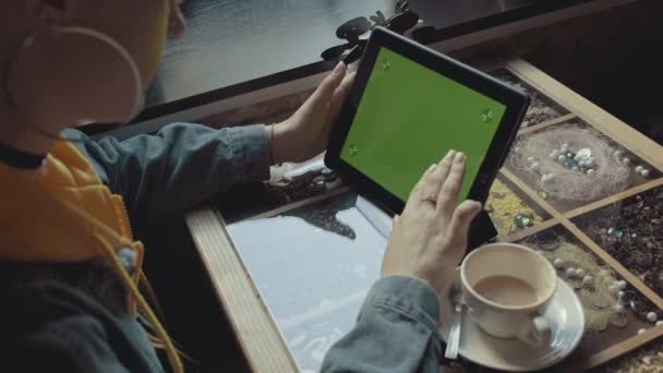 カフェでクロマキーを参照するモバイルデバイス上のタブレット表示緑の画面を使用して女性 手のクローズアップビュー ソーシャルメディアを読む女性 — ストック動画
