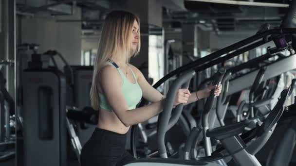 Mulher Jovem Durante Treino Cardio Treinador Elíptico Fit Mulher Loira — Vídeo de Stock