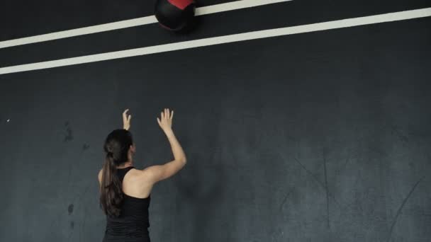 Mujer joven haciendo crossfit pelota de entrenamiento golpea contra la pared con pelota de medicina — Vídeo de stock