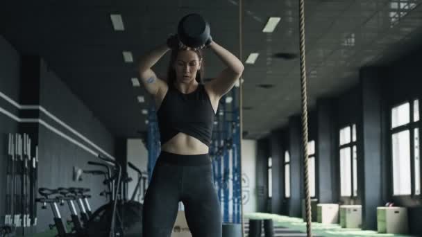 Mujer de fitness haciendo ejercicio de kettlebell durante el entrenamiento crossfit en el gimnasio — Vídeos de Stock