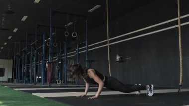 Genç kadın modern spor salonunda burpee tabiat tarihi yapıyor. Güzel kadın burpee tabiat tarihi egzersizleri yapar