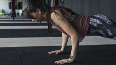 Spor salonunda şınav yapıyor uzun saçlı çekici genç kadın. Kapalı mekanda kaslı atlet kadının yakın çekim. Şınav yapan kadın