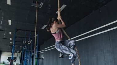 Çekici kadın spor salonunda ip tırmanıyor. Atletik esmer çalışma dışarı kapalı.