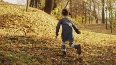 Sonbahar parkında yavaş çekimde koşan bir kız. Copyspace ile tam uzunlukta çekim.