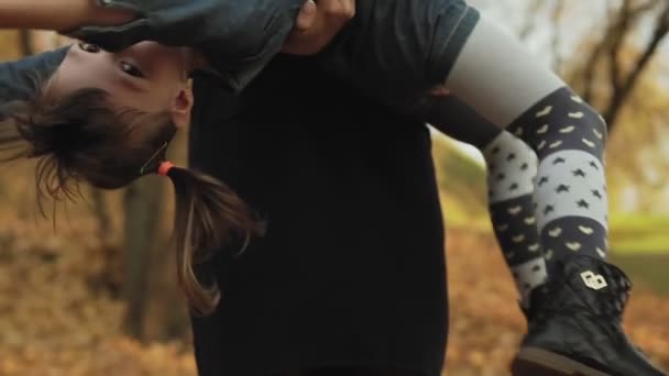 秋の公園で抱き合って笑う若い母と小さな娘 家族は屋外で楽しいです スローモーションでのミディアムショット — ストック動画