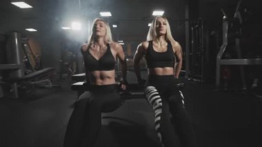 Fitness genç kadın yavaş hareket karanlık spor salonunda Push UPS yapıyor. İki Sportif sarışın kız itme-up performans. Atletik kızlar tezgah üzerinde Triceps egzersiz. Geniş açı