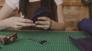 Deri ustası cüzdan yapar. Profesyonel kadın Tanner stüdyosunda hakiki deri ile çalışıyor. Çekim yakın