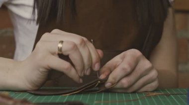 Yavaş hareket iğne ve dizeleri ile profesyonel esnaf dikiş deri cüzdan yakın çekim. El yapımı deri ürünleri.