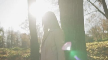 Güneşli parkta çekici genç kadın kamera bakıyor. Açık havada pembe ceket şık kadın orta çekim