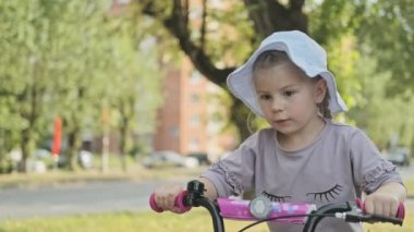 Küçük kız bisikletine binmeyi öğreniyor. Orta çekim bu genç kız sürme üzerinde bisiklet açık havada yaşam tarzı.