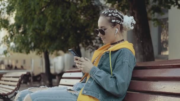 Vacker kvinna lyssnar musik med hörlurar och knacka skärm av smartphone — Stockvideo