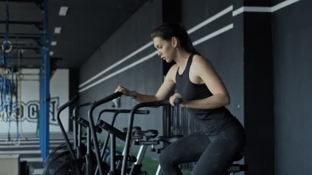 Привлекательная фитнес-женщина на велотренажерах в спортзале. Стройная леди на воздушном велосипеде — стоковое видео