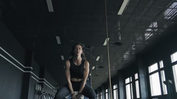 Красивая спортивная женщина делает приседания с гирями наслаждаясь тренировками в тренажерном зале — стоковое видео