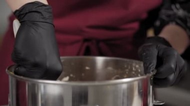 Baker pasta yapmak için metal kasede malzemeyi karıştırır. Havuç ile hamur