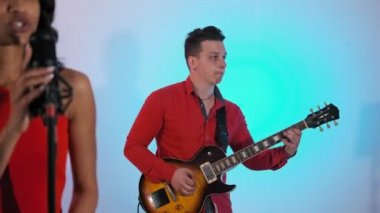 Stüdyodan gitaristi. Rock grubu müzisyenleri. Orta atış. Mikrofon ile Singer kadın