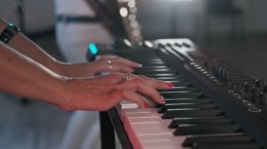 Kadın elleri synthesizer oynuyor. Kadın tuşlara parmaklar dokunur. Caz piyanistin elleriyle yakın çekim