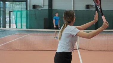 Genç insanlar yavaş hareket ederken tenis oynuyor. Spor ve uzun saçlı güzel kadın tenis top hizmet geniş yapma. Orta çekim Kadın tenis oyuncusu hizmet.