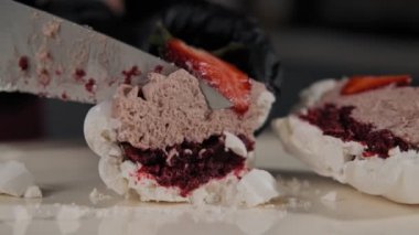 Yavaş hareket krem ve çilek ile fırıncı kesme pasta yakın. Pavlova 'nın bıçak kesme tatlısı