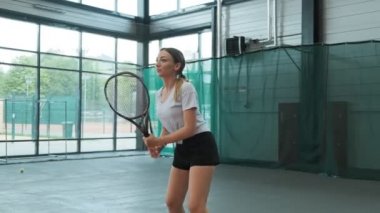 Spor giyim ve uzun saç tenis geniş hizmet topu yapma genç kadın. Yavaş çekimde tenis oynayan kadın. Orta atış tenisçi