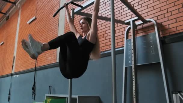 On sports equipment blonde woman doing power exercises with legs raised to body. Female athlete doing exercise training using horizontal bar in slow motion. Wide angle — Stock Footage Sports Equipment Blonde Woman Doing Power Exercises Legs Raised Body Royalty Free Stock Footage