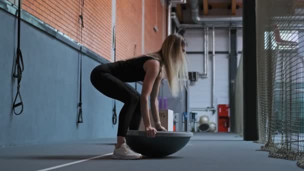 穿着黑色运动服的年轻女子在健身房用慢动作用橡胶半球来推动锻炼 全长拍摄 可爱的女性训练在健身房 — 图库视频影像