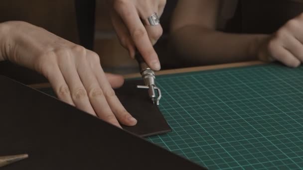 장인은 특별한 도구를 구멍에 그립니다 마스터는 워크샵에서 지갑을 만든다 슬로우 — 비디오