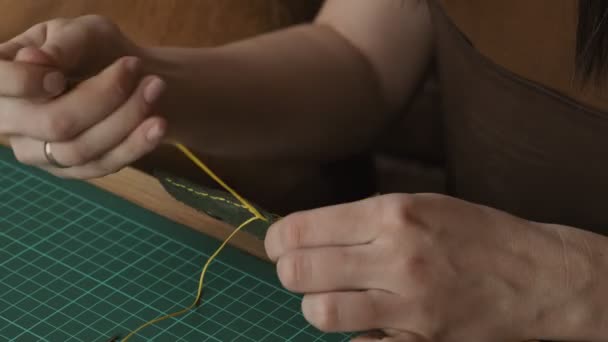 革の縫製プロセスのクローズアップショット 針と糸で手をプロの女性職人 — ストック動画
