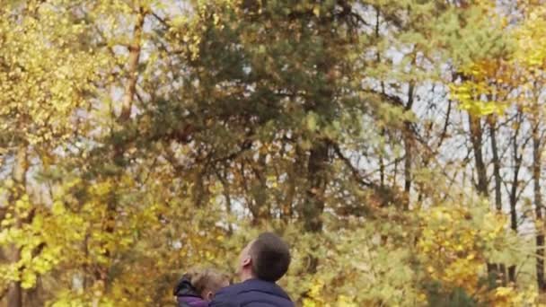 秋の公園で一緒に遊ぶ父と娘 パパは子供を投げ捨てるスローモーションで一緒に楽しむ家族 — ストック動画